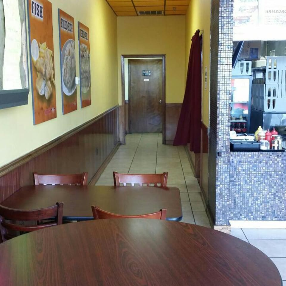 Interior view of a casual restaurant with yellow walls, dark wood tables, and a service counter.