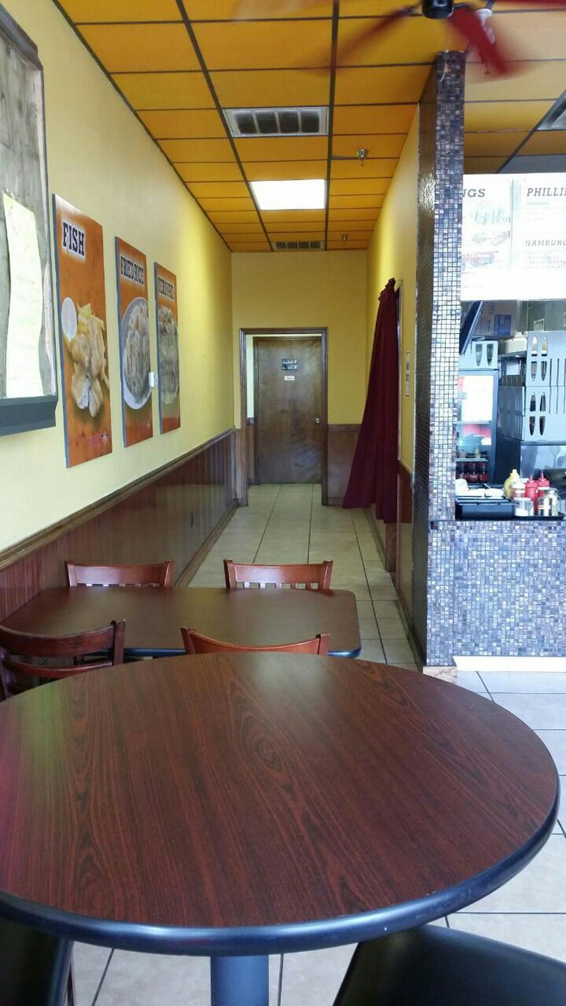 Interior view of a casual restaurant with yellow walls, dark wood tables, and a service counter.